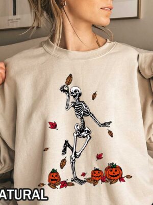 Vintage Halloween Skeleton Dancing Sweatshirt A happy skeleton holding a fall tree leaf and dancing around Jack-o-lantern carved pumpkins on a vintage Halloween sweatshirt